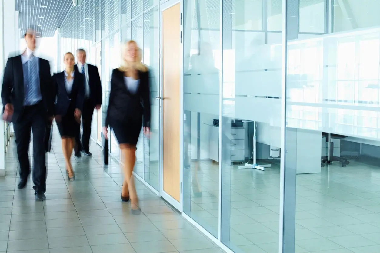 A group of people walking in front of glass walls.